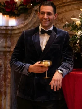 Garrett Marcantel smiling in a navy velvet blazer and bow tie while holding a gold goblet at a holiday event