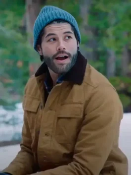 A bearded man looking surprised in a brown canvas work jacket with a dark brown collar and a blue knit beanie