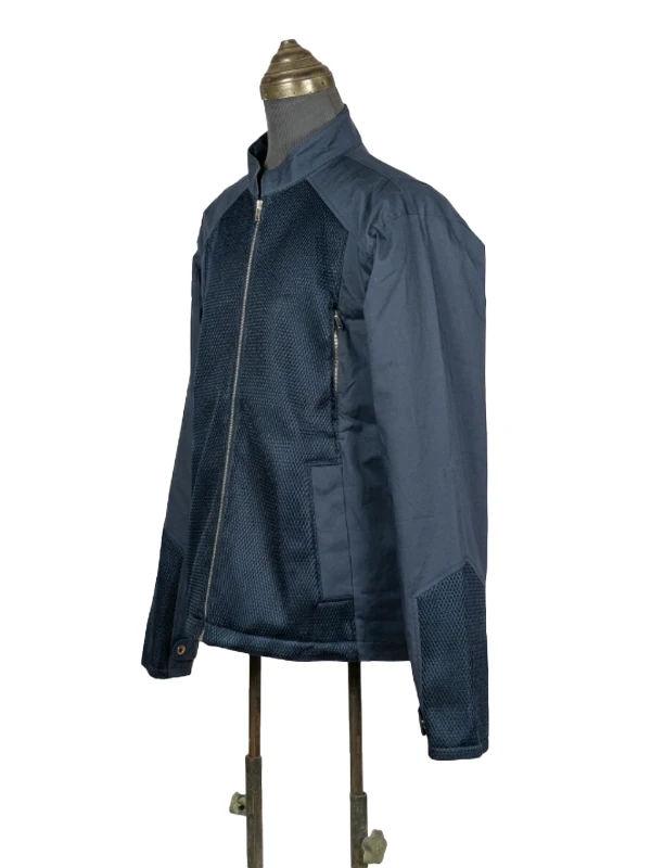 Side-angle profile shot of the navy blue Captain America civilian jacket, showcasing the mixed-media textured mesh panels on the chest and lower sleeves.