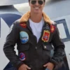 Tom Cruise posing in a top gun maverick leather jacket, highlighting the classic flight design and various naval patches against a bright backdrop.