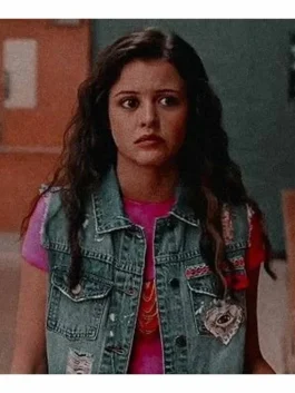 Sleeveless distressed denim vest featuring colorful embroidered patches, decorative pins, and white paint splatter accents.