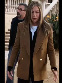 The Morning Show Alex Levy Camel Coat worn by Jennifer Aniston in an outdoor scene, showcasing the elegant brown wool coat with gold buttons and sleek tailored design.