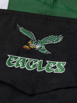 Close-up of the high-quality embroidery on an eagles jacket starter, showcasing the vintage eagle logo and stylized team text in green and white.
