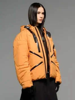 Side pose of a model wearing the Death Stranding 2 jacket in orange with unique zipper detailing.
