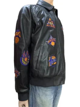 Black leather bomber-style jacket on a hanger, showcasing detailed embroidery and athletic patches.