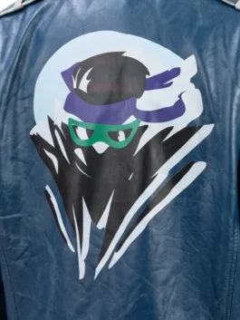 Close-up of the large printed graphic on the back of the blue Johnny Cage leather jacket, featuring a stylized ninja design with a purple headband and green glasses.