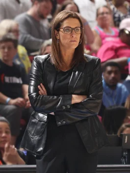 Stephanie White in black leather blazer, hands on head.