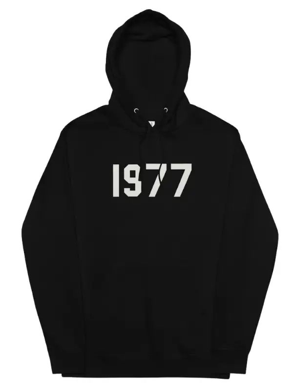 A solid black Fear of God Essentials hoodie with the large numbers "1977" printed in a contrasting light color on the chest.