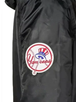 A detailed look at the New York Yankees x Alpha Industries x New Era Bomber Jacket. This garment includes a functional hood, a robust central zipper, and a utility pocket on the left arm. The black colorway is accented by crisp white embroidery and commemorative patches that signify this unique streetwear collaboration.