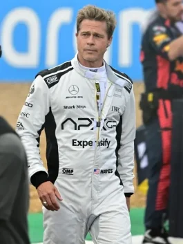 Brad Pitt wearing the Grand Prix Brad Pitt F1 Racing Jumpsuit in a Formula One pit lane, showcasing the sleek white and black racing suit design.