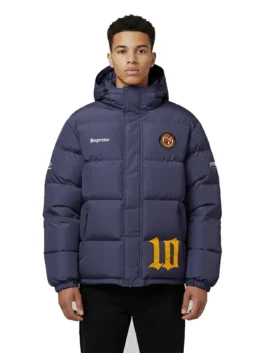 Front view of a model wearing the navy blue Supreme Umbro Down Puffer Jacket with a hood. It features 'Supreme' on the chest, a round patch emblem, and a large yellow '10' graphic near the hem.