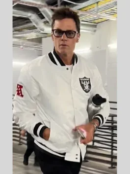 Tom Brady wearing the Las Vegas Raiders white jacket (a white bomber jacket style) while walking, with his hands in the pockets.