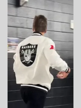 The back of Tom Brady wearing a white Raiders bomber jacket with the large Las Vegas Raiders shield logo and 