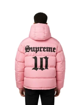 Back view of a model wearing the pink Supreme Umbro Down Puffer Jacket with a hood. It has a large black 'Supreme' and '10' graphic printed on the back.