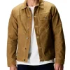 Man wearing Flint and Tinder Waxed Trucker Jacket in tan color, a durable Huckberry waxed trucker jacket made from premium waxed canvas for rugged outdoor and casual wear.