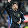 Lionel Messi waving to fans, wearing the official Argentina national team hoodie in black with blue stripes, a potential last home game apparel, showcasing Messi Argentina fan gear.