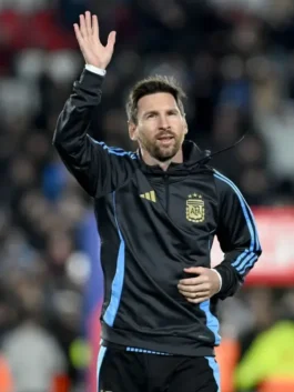 Lionel Messi waving to fans, wearing the official Argentina national team hoodie in black with blue stripes, a potential last home game apparel, showcasing Messi Argentina fan gear.