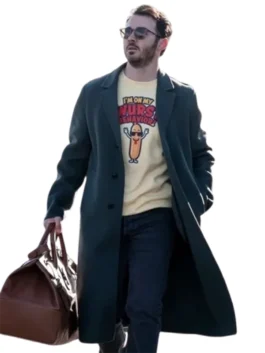 Kevin Jonas in a dark forest green peacoat over a striped shirt, looking off-camera while holding a small black object, possibly a phone.