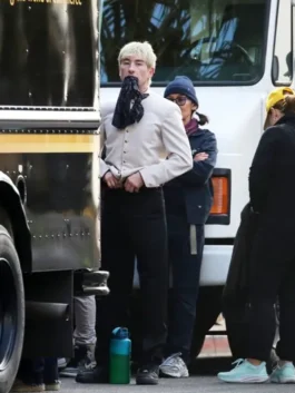 Barry Keoghan dressed in the Crime 101 hotel uniform, a beige bellhop jacket with name tag and dark trousers.