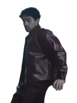 Joe Jonas is shown in a side-profile view, leaning down while wearing a dark maroon or burgundy leather bomber jacket and matching pants. The jacket has a zip front and a high collar.