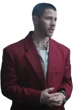 Close-up of Nick Jonas wearing a bold red blazer over a pale, striped collared shirt that's open at the neck. He is looking off to the side with his hands clasped in front of him.