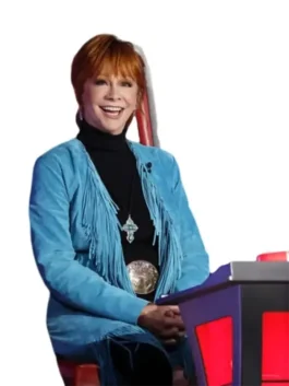 Reba McEntire blue suede fringe coat on The Voice S28, smiling and wearing a large western belt buckle.