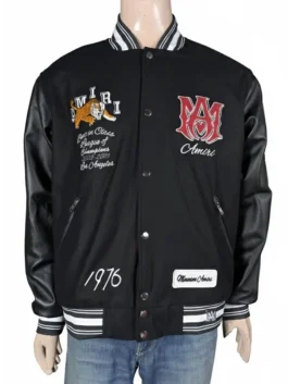 Front view of a premium black varsity jacket on a mannequin featuring leather sleeves, a striped rib-knit trim, and bold embroidered patches on both sides of the chest.