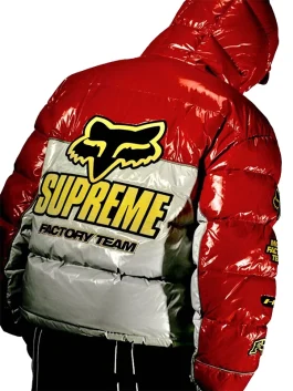 Model wearing red Supreme Fox Racing shiny down puffer jacket with bold yellow logo, stylish insulated down jacket for winter.