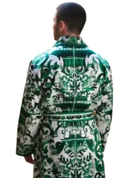 Nick Jonas facing away, wearing the distinctive green robe from the A Very Jonas Christmas movie. The robe features an ornate, green and white baroque pattern. Nick Jonas Robe A Very Jonas Christmas.