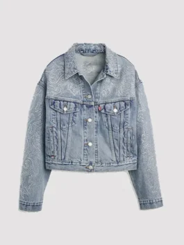 Front view of the light wash Beyoncé x Levi's Shrunken 90s Denim Trucker Jacket. The cropped jacket is embellished with an intricate, Western-inspired paisley pattern made of rhinestones across the shoulders, collar, front body, and sleeves. The jacket has a relaxed fit and traditional denim jacket pockets.
