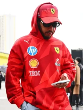 Lewis Hamilton looking at his phone wearing sunglasses and a matching red cap, styled in the Lewis Hamilton Las Vegas F1 pullover hoodie featuring the HP and Shell logos.