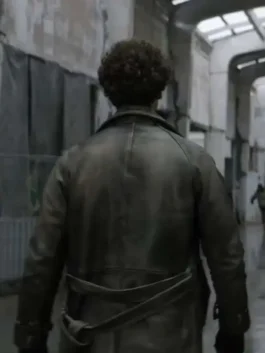 Back view of Emile's distressed leather coat, showing the waist belt and yoke, as he walks away down an abandoned, grim hallway.