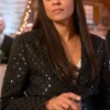 Woman wearing a black sequin dot blazer in a festive indoor setting, holding a glass.