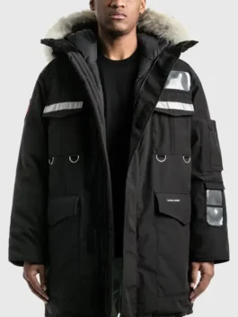 Front view of a men’s black parka jacket with fur-trim hood, reflective panels, and multiple utility pockets.