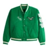 Front of a green Philadelphia Eagles varsity bomber jacket with an eagle patch, "Fly Eagles Fly" embroidery, and the numbers '46 on the left sleeve.