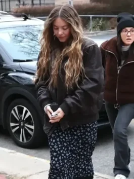 The Housemaid Sydney Sweeney bomber jacket in a dark distressed leather style, paired with a floral dress on the Montclair movie set.