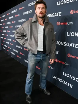 A full-length view of The Housemaid Brandon Sklenar grey jacket. This Andrew Winchester grey wool jacket is styled with blue jeans and boots.