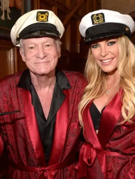 Close-up of a hugh hefner costume for men and a woman in a womens hugh hefner costume, both wearing a red satin robe and a captain's cap. Hugh hefner halloween couples theme.
