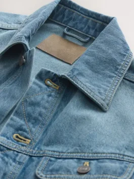 Detailed view of the collar and neckline of this blue denim style jacket, showing the premium fabric texture and authentic brown branded inner tag.