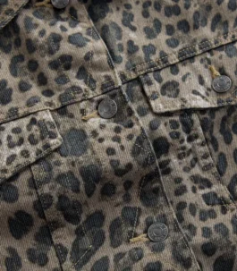 Detailed shot of a denim jacket with leopard print, highlighting the metal buttons, flap chest pockets, and precision contrast stitching.