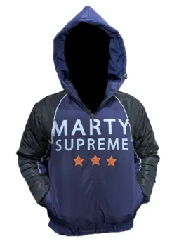 Nikki Glaser on the set of Marty Supreme 2026 wearing an oversized navy blue and black jacket while holding a table tennis paddle.