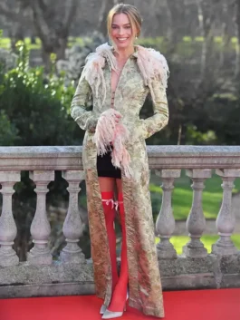 Margot Robbie wearing a John Galliano long trim coat in vintage floral brocade with pink feathered trim on a red carpet.
