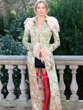 Margot Robbie in an archival John Galliano coat featuring a long silhouette, feathered collar, and vibrant red stockings.
