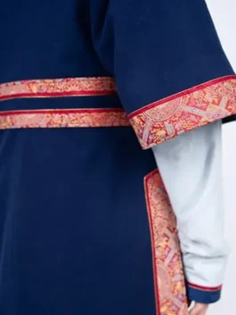 Detailed view of the winter games 2026 team mongolia womens uniform, showing the red and gold patterned trim on the navy blue traditional deel.