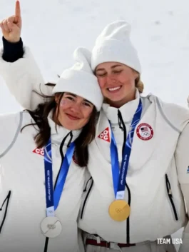 athletes Jaelin Kauf and Elizabeth Lemley celebrate while wearing the official Nike Winter Olympics 2026 Team USA Puffer Jacket on snow.