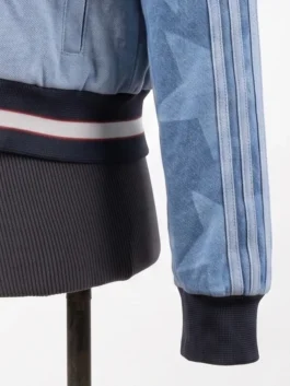 Zoomed-in view of the ribbed knit waistband and cuff on the Adidas Denim Graphic Varsity Bomber Jacket, showcasing the faded star patterns.