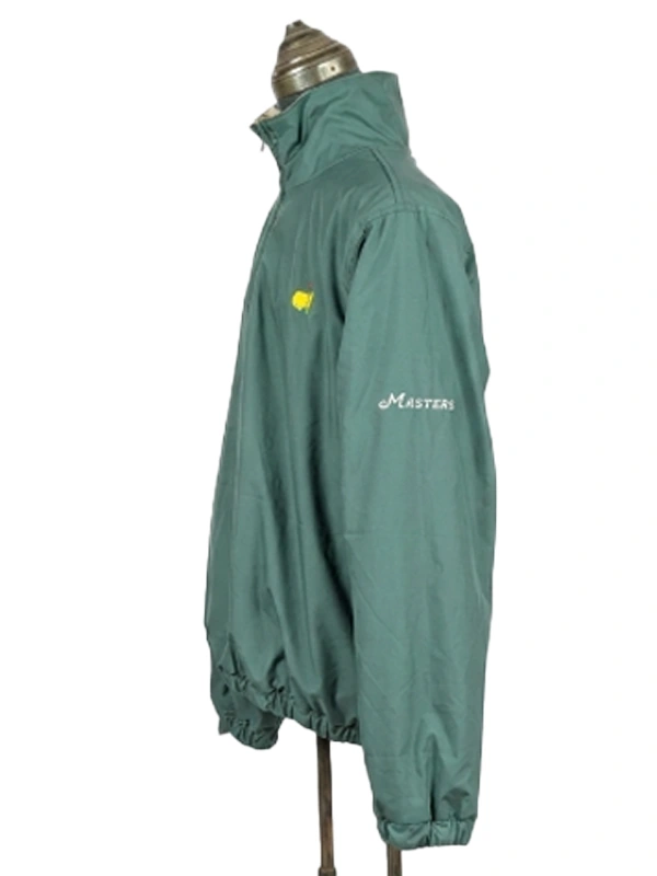 Three-quarter side angle display of the solid green side of the Masters reversible windbreaker jacket, featuring cursive script arm embroidery.