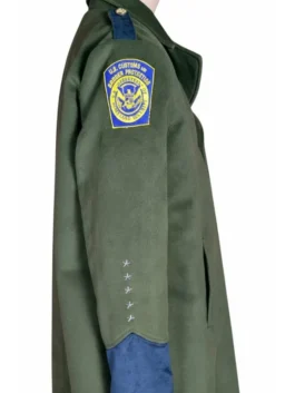 Right profile view of a dark green uniform trench coat on a mannequin featuring the shield-shaped U.S. Customs and Border Protection insignia and star embroidered sleeve detailing.