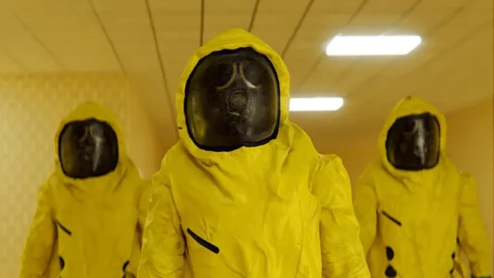 Async Research Institute scientists in yellow hazmat suits and gas masks standing in the Backrooms hallway in the 2026 A24 horror film Backrooms