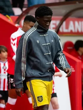 Manchester United player wearing grey Adidas CNY jacket and yellow Man United shorts during Matchday 36 Premier League walkout